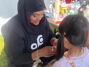 face painter smiling with little girl in front of her