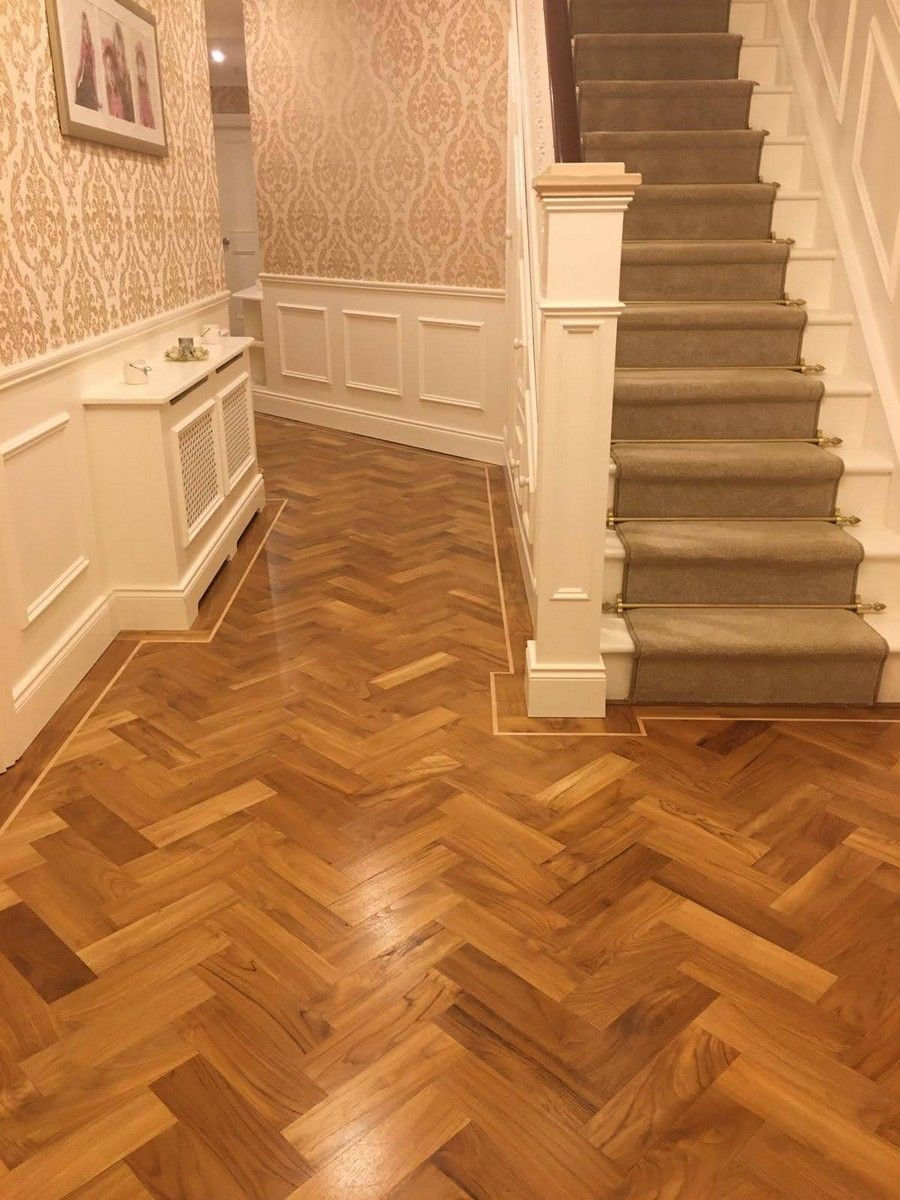 Solid teak herringbone with maple inlay installed in a traditional furnished hallway