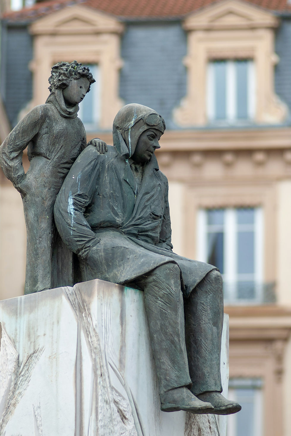 Bronze statue of The Little Prince standing behind seated aviator with hand on his shoulder