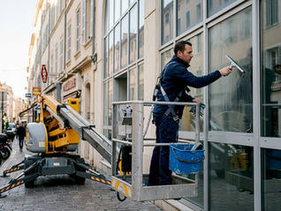 Un professionnel équipé d’une nacelle en train de laver les vitres d’un immeuble dans le Var