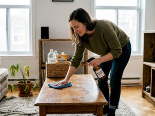 Une femme prend soin de sa table basse en la nettoyant avec des produits respectueux de l’environnement.