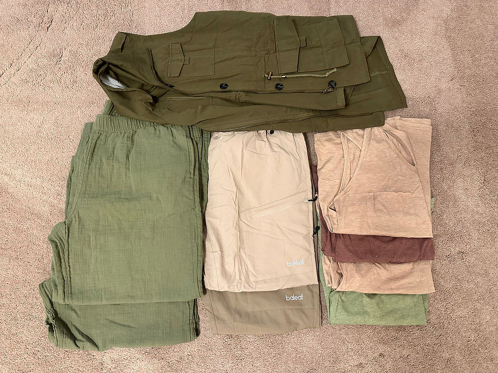 Folded clothing items on beige carpet, including green pants, a tan and green jacket, and shirts in beige, brown, and green.