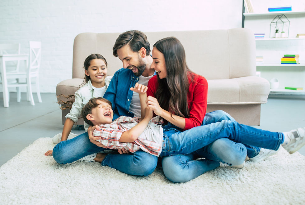 Happy beautiful young parents are smiling, hugging and playing with them kids at home toge