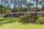 Charming entrance to Mosswood with manicured lawns and sleek architecture.
