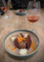 A chocolate dessert in a pottery bowl served with plum liqueur
