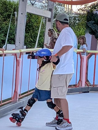 A man holds up a boy on roller skates whose legs are going in opposite direction