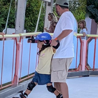 A man holds up a boy on roller skates whose legs are going in opposite direction