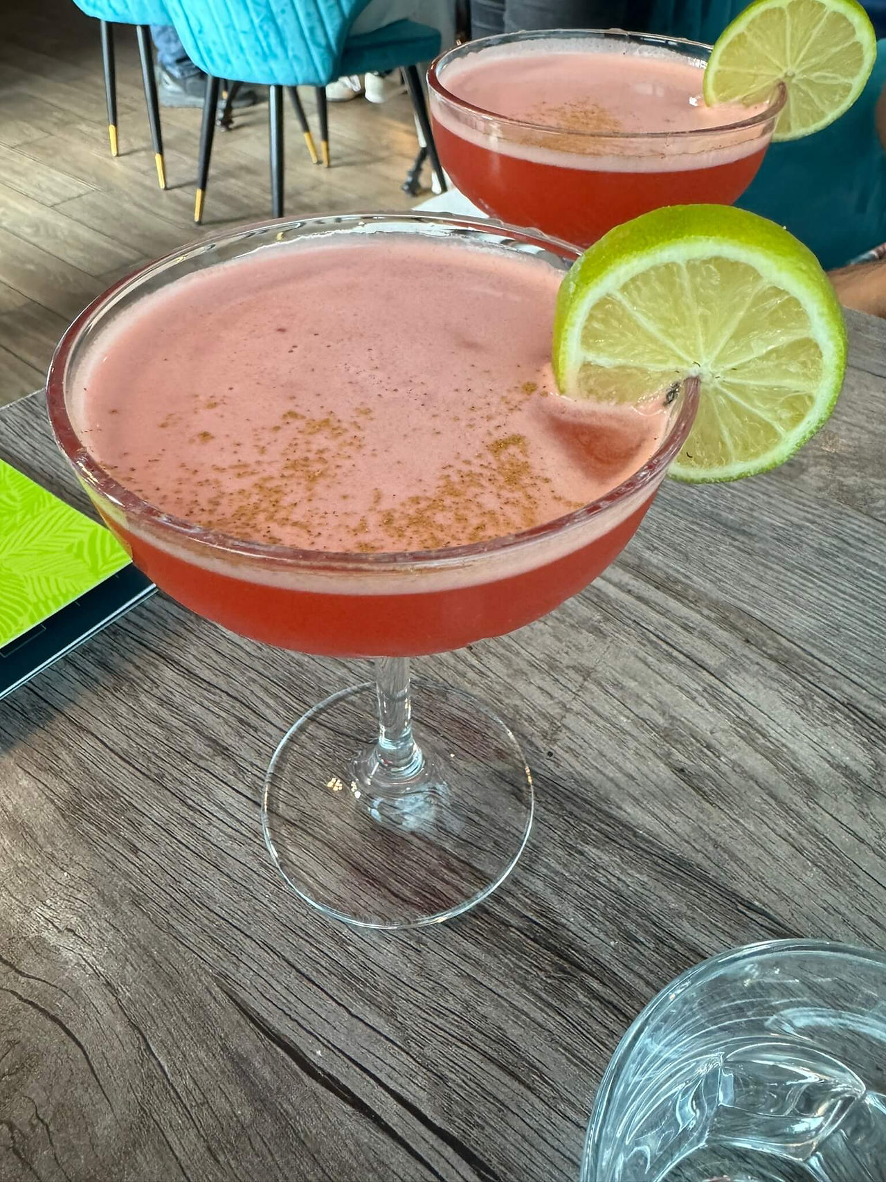 Image of a cocktail with a slice of lime on the rim.
