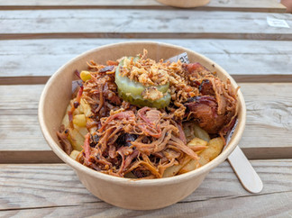 Shredded pork over French fries with sliced pickled gherkin