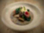 food prettily plated on a round pottery plate