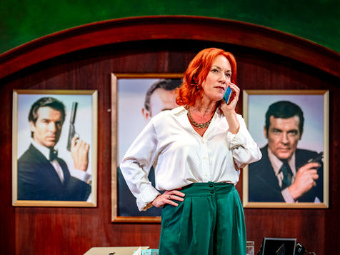 A woman standing on the phone, in front of images of former James Bond stars