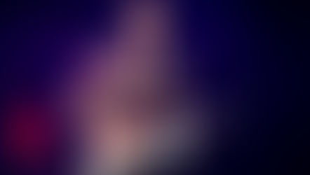 Musician in a colourful shirt plays a keytar on stage, singing into a microphone. A dimly lit background with a faint clock is visible.