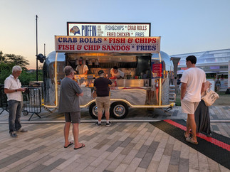Man standing waiting at a food truck selling crab rolls and fish and chips