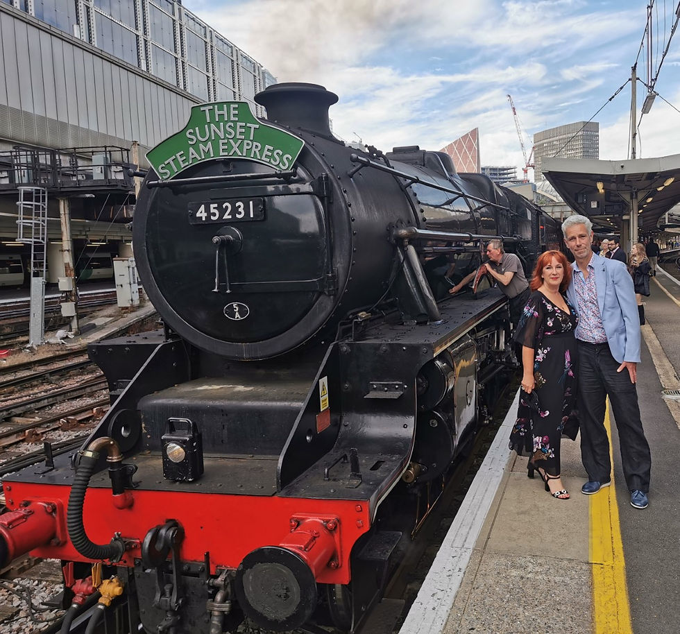 Woman and man standing next to steam train on the platform waiting to board