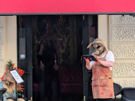 Halloween display outside Purgatory Cocktail Bar and Escape Rooms, with two masked figures, pumpkins, and a red awning sign.