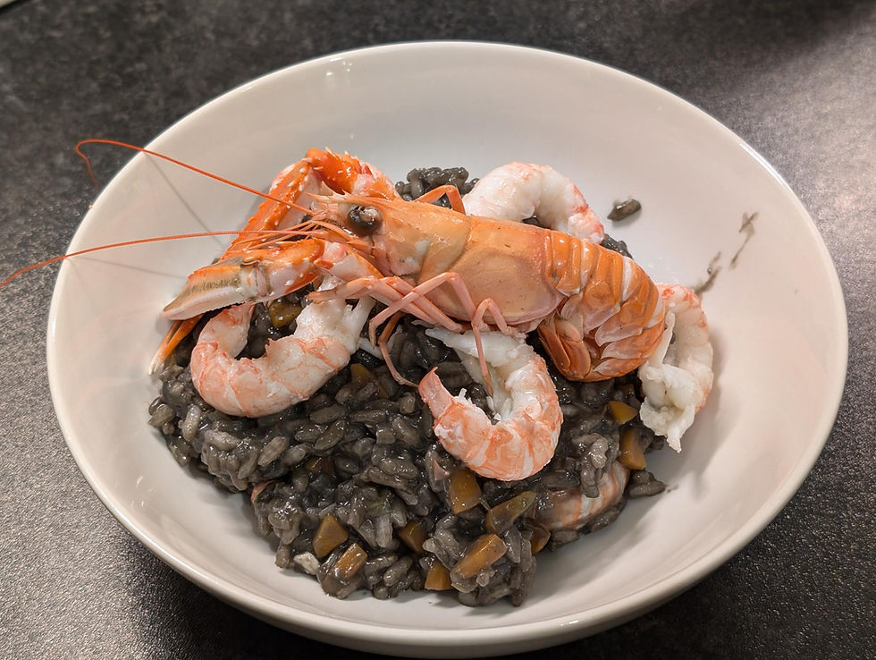 A bowl of squid ink risotto topped with whole langoustine