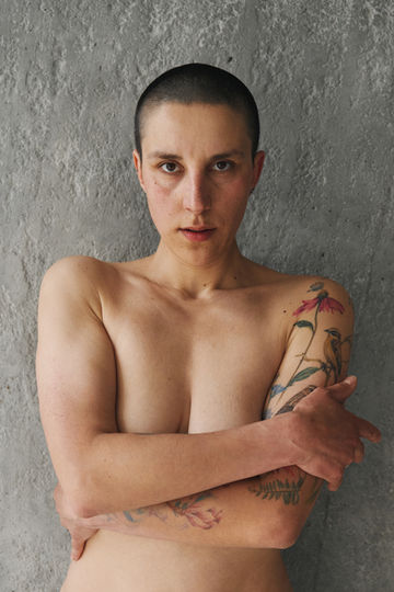 Close portrait of Sandra Kosh facing the camera against a textured grey wall