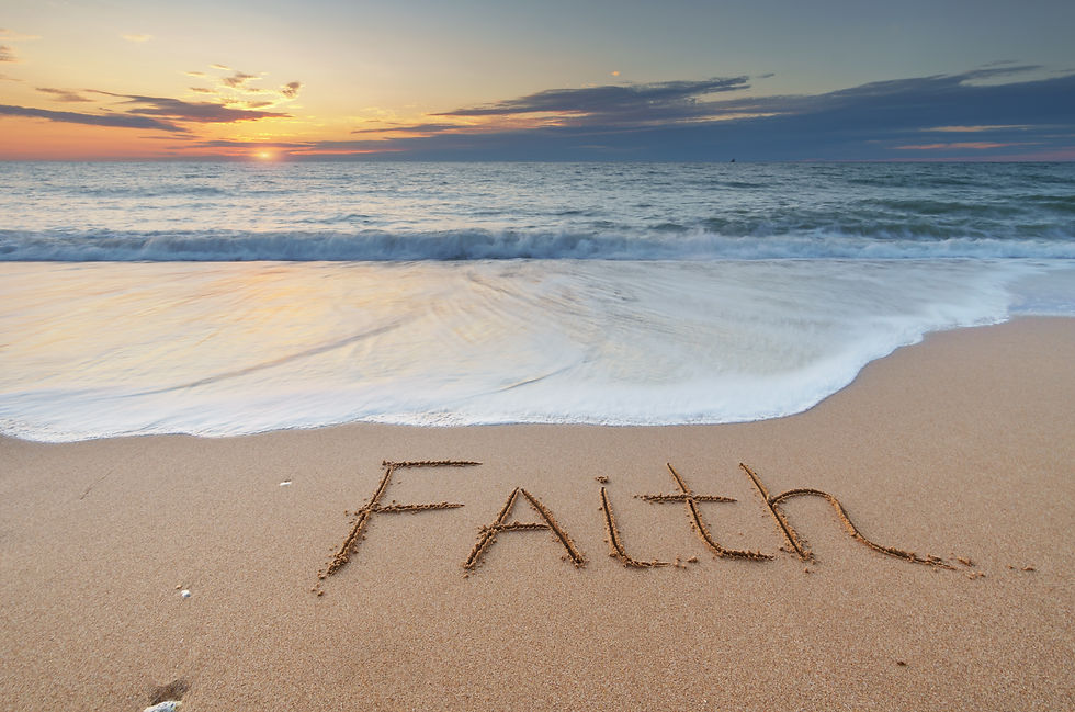 The word faith written in the sand with the sea in the background