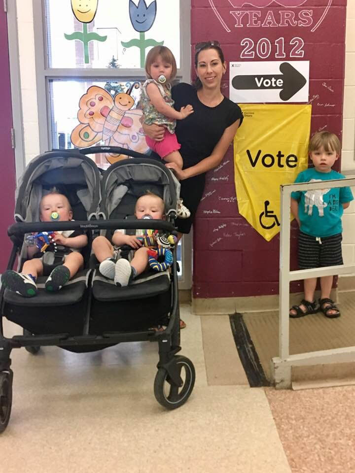 Parent with children and stroller near voting signs