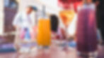 Colorful drinks on an outdoor table, with a waiter in the blurred background. Sunny day with a warm, relaxed atmosphere.