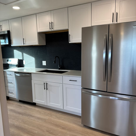 Modern kitchen with white cabinets, stainless steel appliances and black faucet.