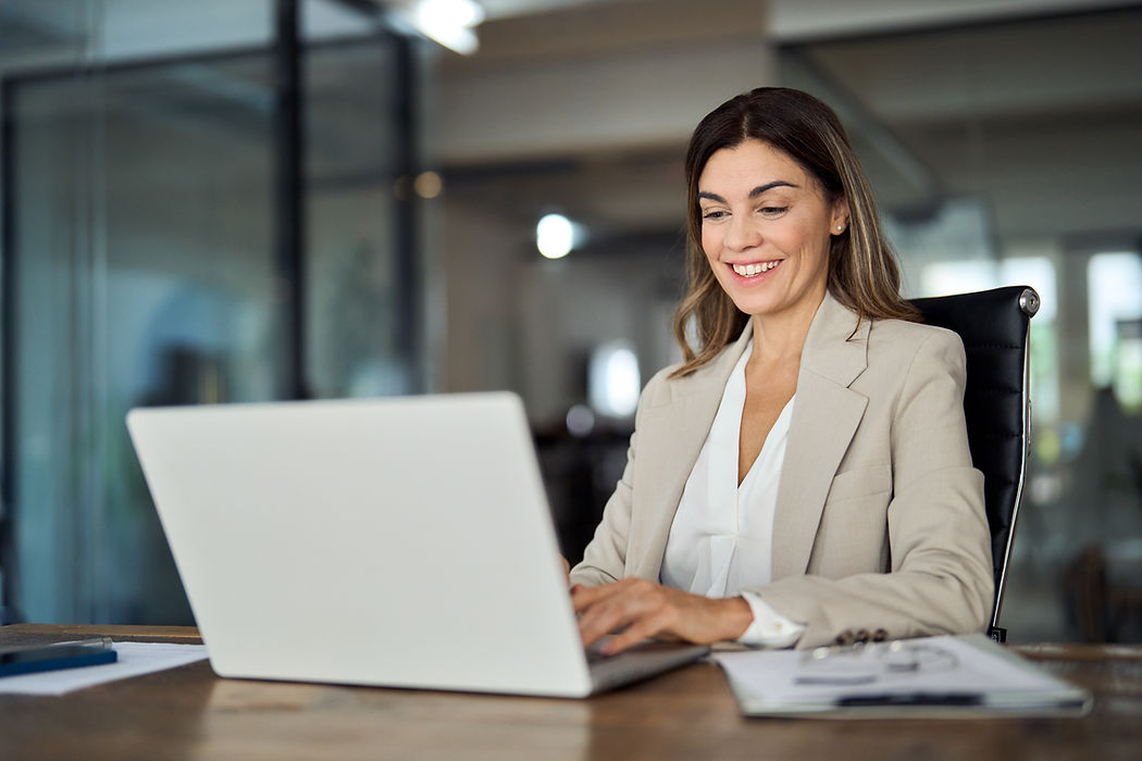 Happy mature business woman entrepreneur in office using laptop at work, smiling professio