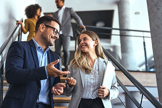 Professionals in a modern office environment discussing work-related matters on a staircas