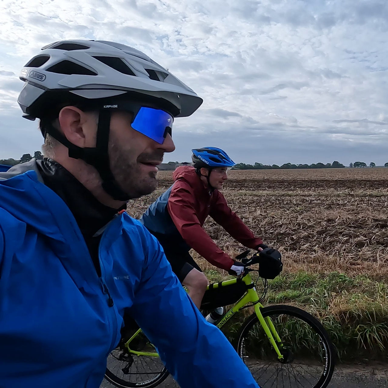 Two guys riding bikes next to a field