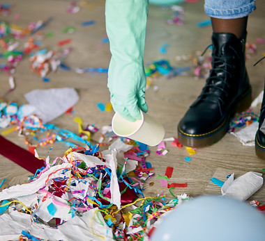 woman-cleaning-mess-floor-room-after-party-removes-garbage-from-floor-disposable-cups-bag-
