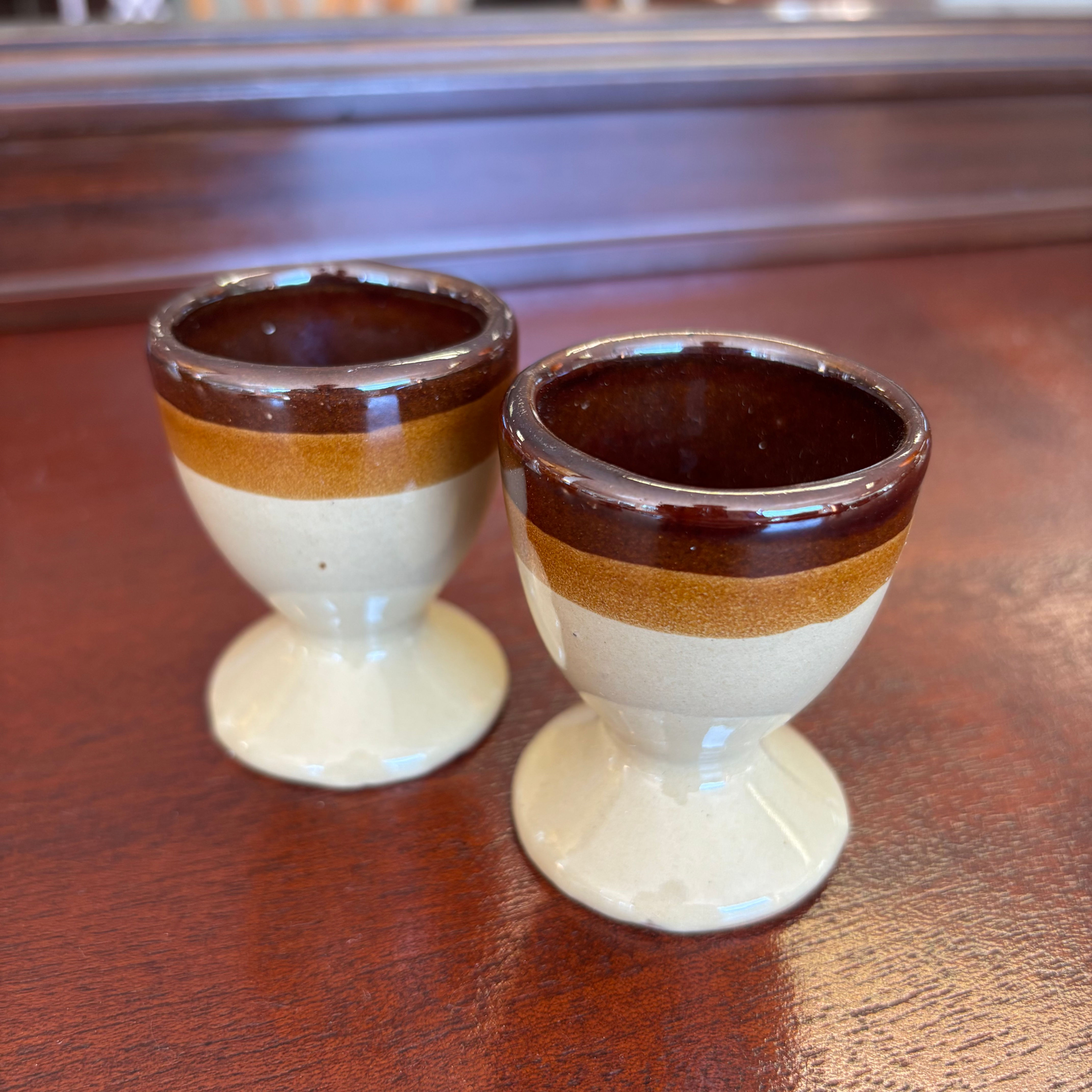 A pair of vintage 1970s stoneware egg cups with a brown and beige two-tone