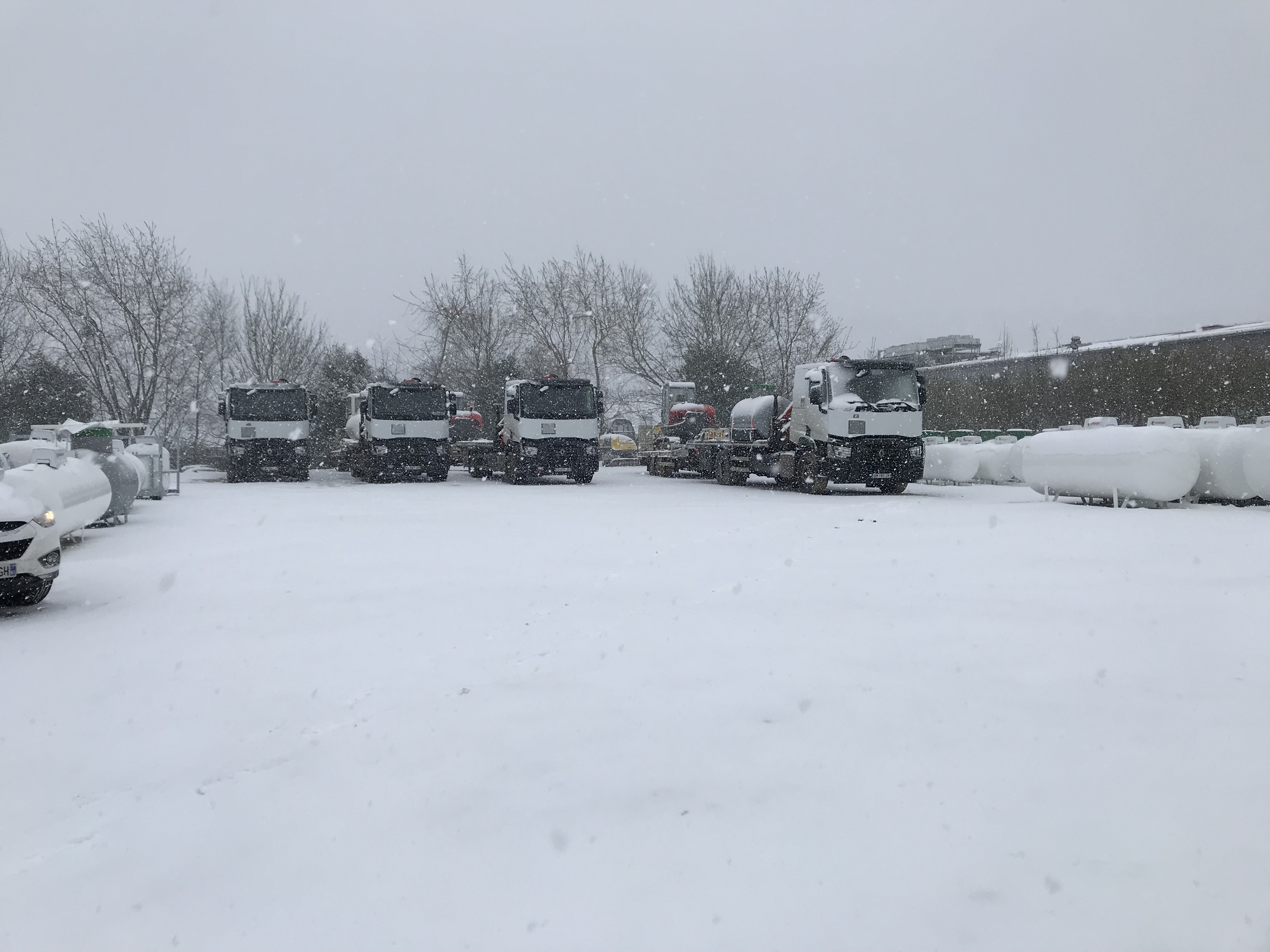 Camions et réservoirs dans une cour enneigée, photographie publiée par Sotrasur Auneuil.
