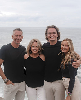 Happy family posing during a beach family photoshoot in San Diego with ocean views.