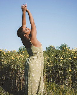 A serene outdoor portrait of a woman in a flowing green dress, basking in golden sunlight among vibrant yellow wildflowers during a portrait photography session, capturing the essence of nature photography with warm tones and a dreamy aesthetic.