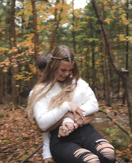 Joyful couple sharing a playful moment in a scenic autumn forest capturing love laughter and romance perfect for engagement wedding or lifestyle photography inspiration.
