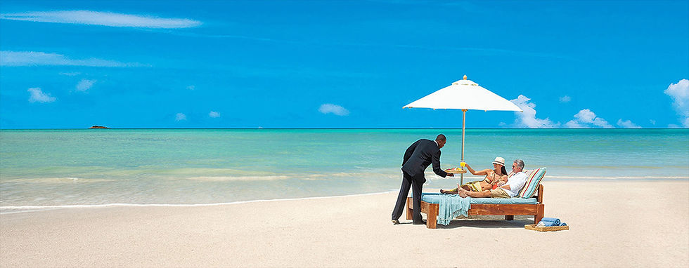 Sandals Resorts Butler delivering drinks to couple on the beach