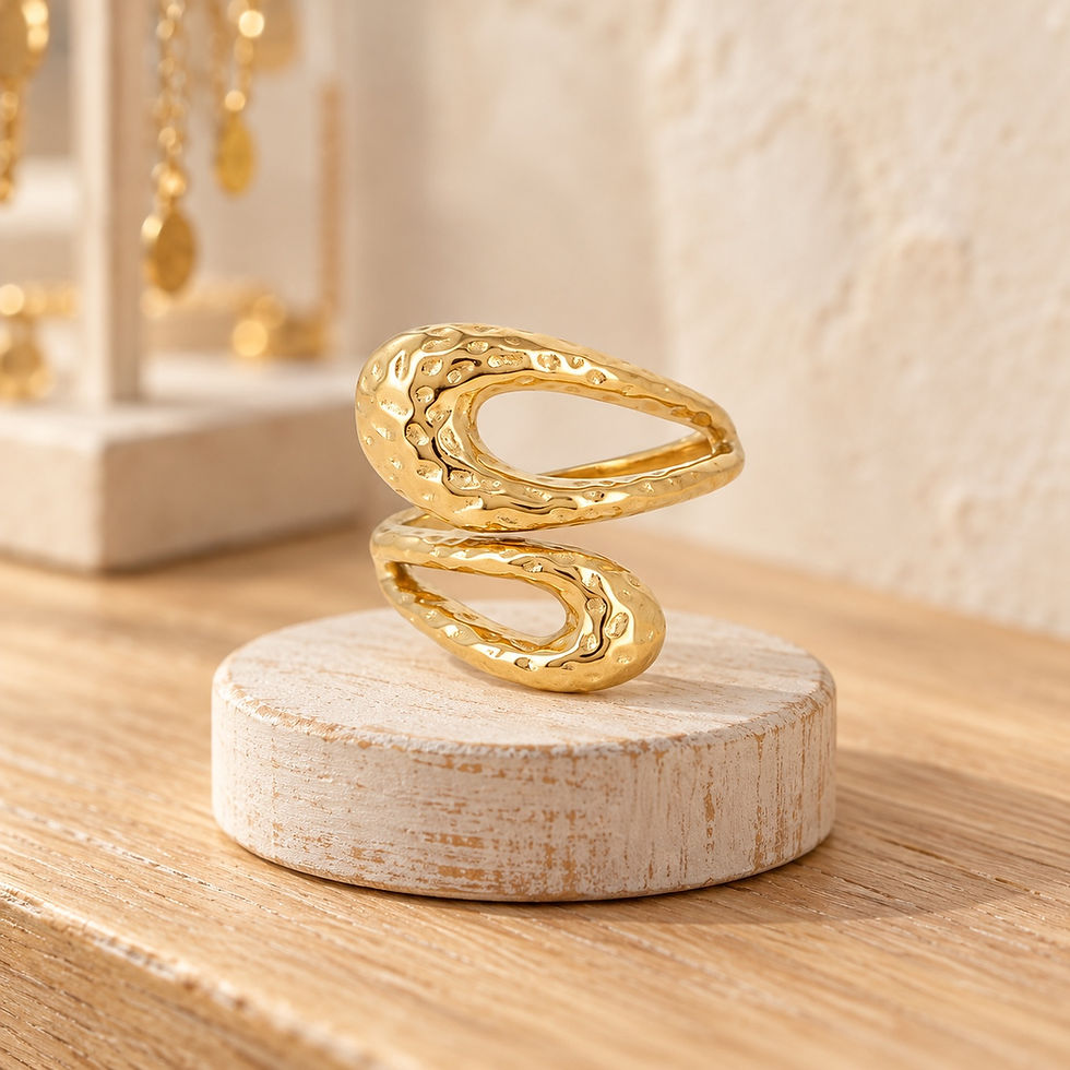 Bague ouverte martelée BOHM PARIS dorée à deux formes ajourées, présentée sur un socle beige.