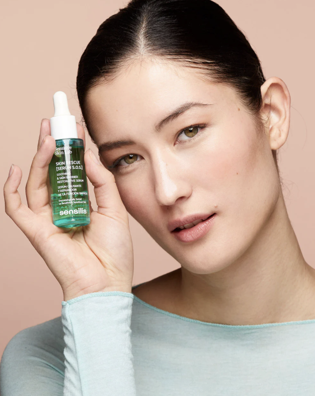 A minimalist skin serum bottle positioned next to a calm stream of water.