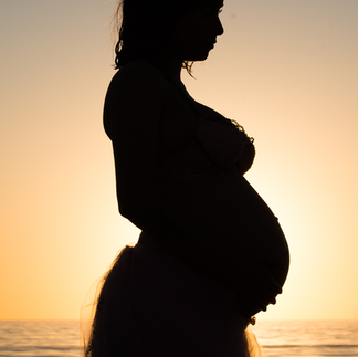 Silhouette of pregnant mother at the beach during sunset