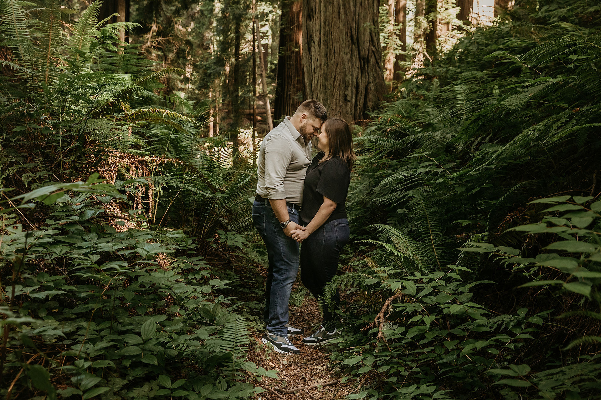 Couple kiss on a trail at Sequoia Park for their engagement photoshoot