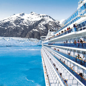 A cruise ship gliding through turquoise waters, flanked by snowy mountains and glaciers, with passengers enjoying the scenic view.