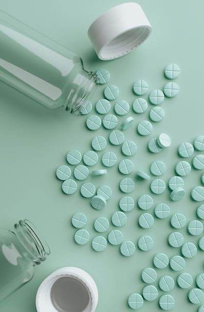 Light green tablets scattered across a mint-colored surface with open pill containers nearby.