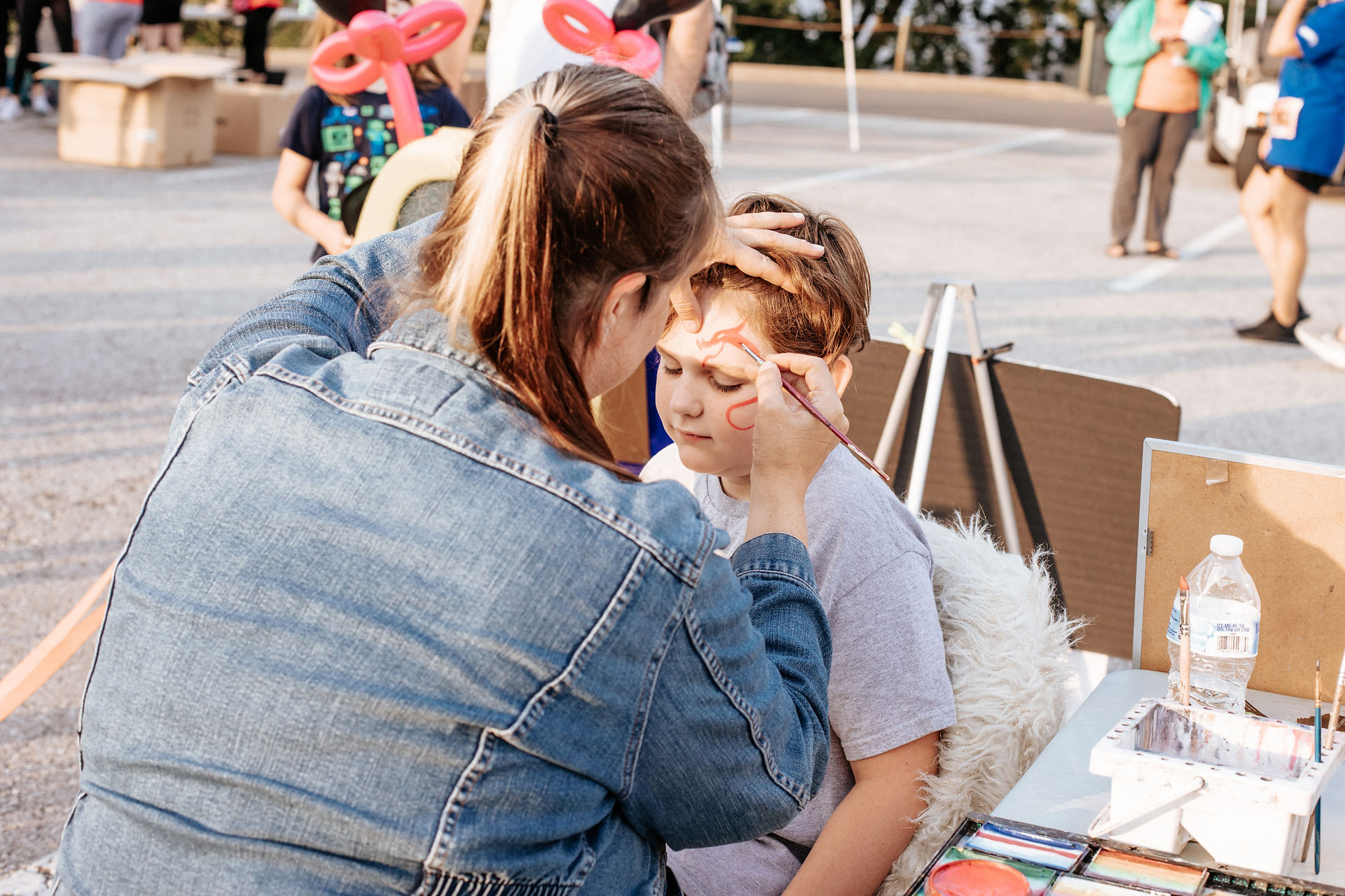 Love Fund 5k Face Painter in Action Paints a Rainbow and Clouds on a Child's Face at Worlds of Fun