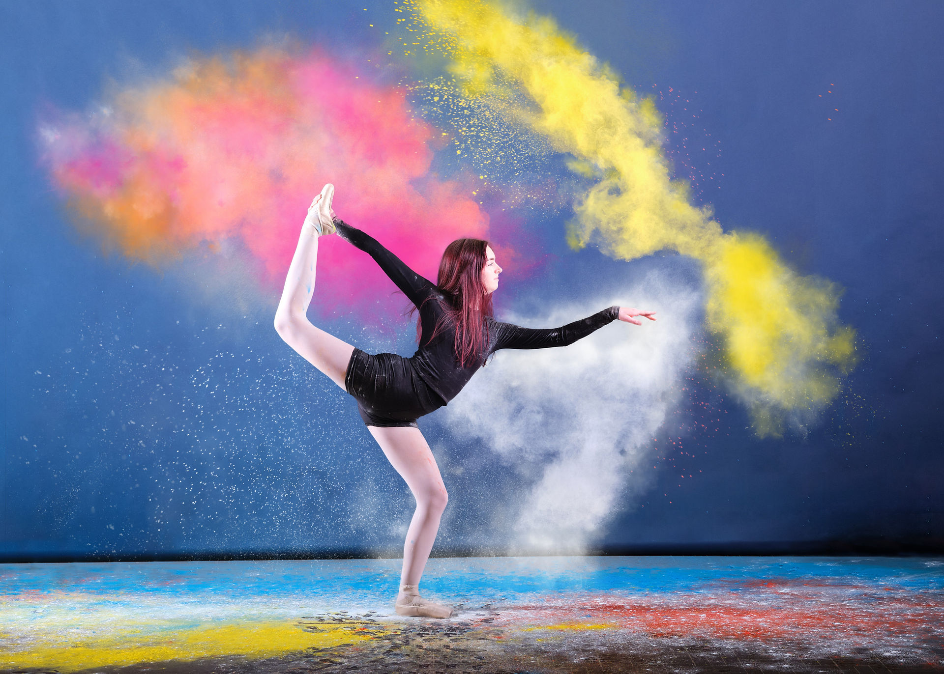Young girl in ballet pose throwing coloured powder for the dance photography shoot.