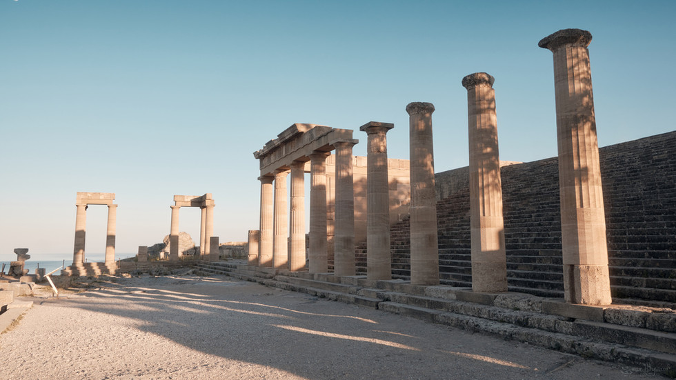 The low sun creating long shadows from the columns of the Acropolis in Lindos