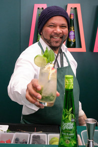A barman smiling whilst serving a cocktail in the bottle green bar