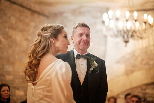 a bride and groom stood in the ceremony room at thornbury castle with the groom smiling at the camera