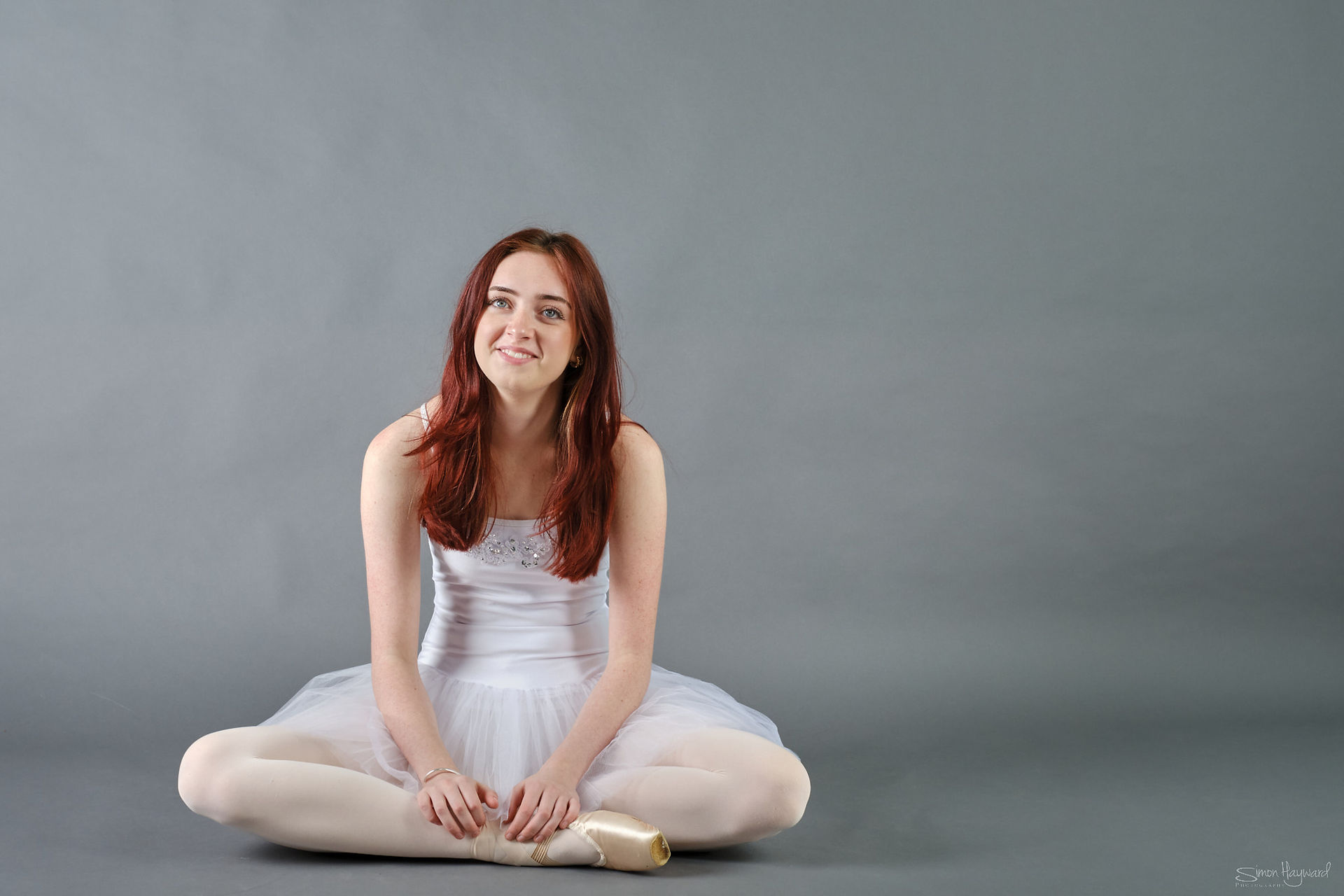 Young girl in ballet tu tu smiling sat on floor after ballet photoshoot