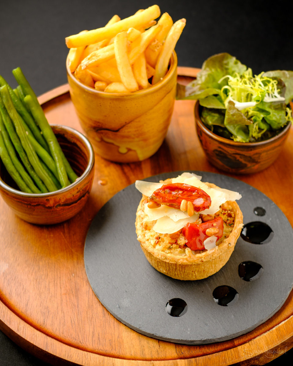 A small pie served with chips, beans and a side salad