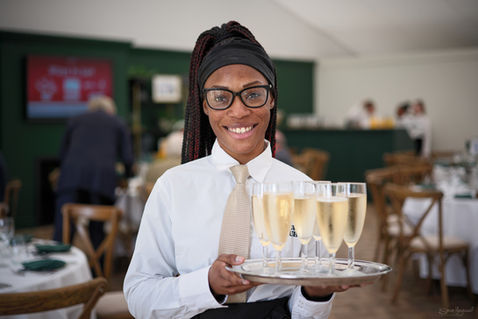 A young waitress holding a try of full champagne glasses