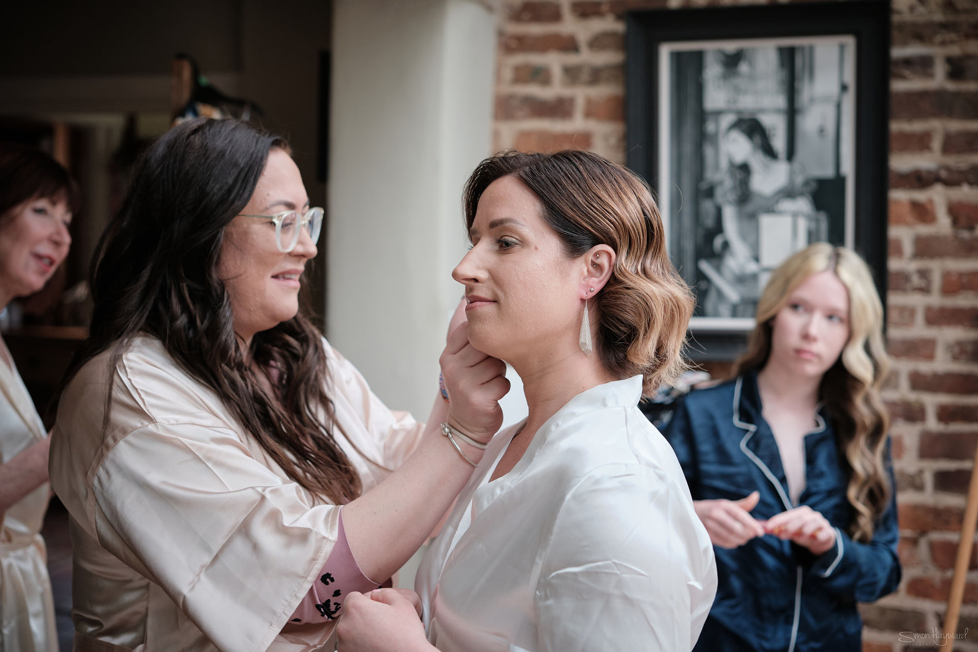 A bride receiving help to put her ear rings in